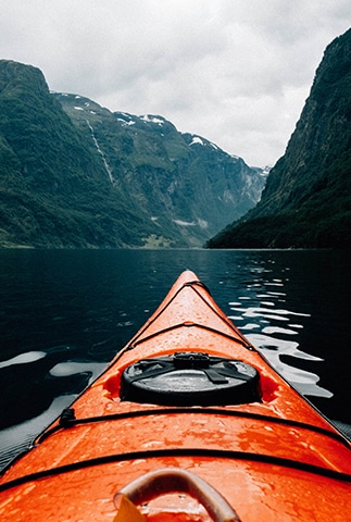 Image de la partie avant d'un canoë voguant sur un lac entouré de montages pour illustrer la capacité de chacun à contrôler sa vie et affronter les intempéries - responsabilité personnelle - Ecole de PNL de Lausanne - EPNLL